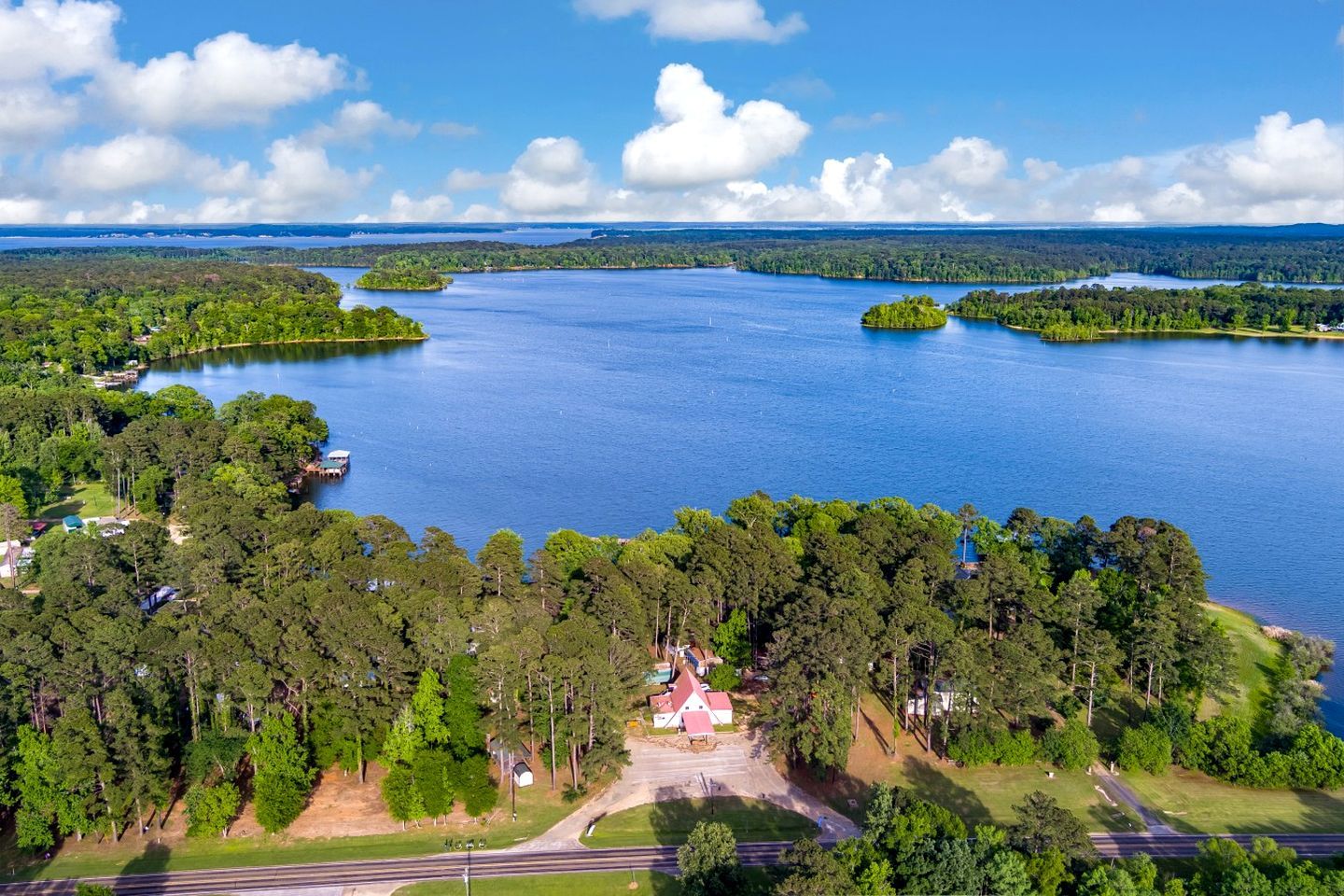 A large body of water surrounded by dense forest, with a small building in the foreground.