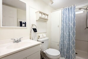 Un bagno con lavandino, wc e tenda della doccia, tutto in bianco.