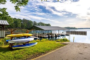 Une jetée au bord du lac, avec des canoës, un espace de repos abrité et une zone herbeuse avec un sentier.