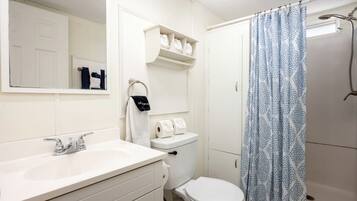 Une salle de bain avec un lavabo blanc, des toilettes et un rideau de douche.