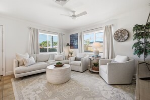 Ein Wohnzimmer mit einer Couch, Sesseln, einem Couchtisch und einer Pflanze.