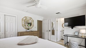 A bedroom with a bed, a dresser, a mirror, a television, and a ceiling fan. - Private Tropical Oasis • Heated/Cooled Pool (Naples)