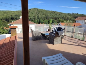 Eine Terrasse mit Korbmöbeln, einem kleinen Tisch und einem weißen Stuhl.