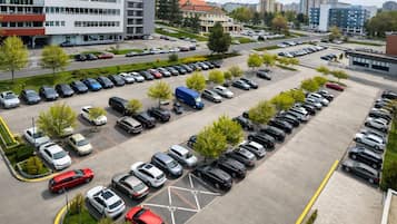 A multi-story parking structure with rows of parked cars and a few trees.