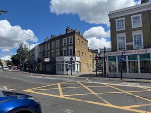 A street view with buildings, a 'RISING PEARL' sign, and a 'K.C. Continental Stores' sign. - Two-bedroom Flat Sleeps 8 (London)