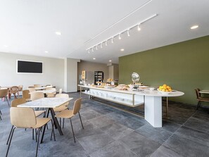 A modern dining area with a central island, multiple seating arrangements, and a buffet setup.