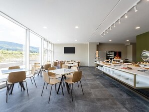 A modern dining area with a long counter, multiple tables, and chairs. - B&B Hotel Ascoli Piceno (Ascoli Piceno)