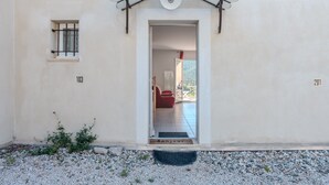 Une entrée d’immeuble avec une porte, une fenêtre grillagée et une plaque indiquant le numéro de l’immeble.