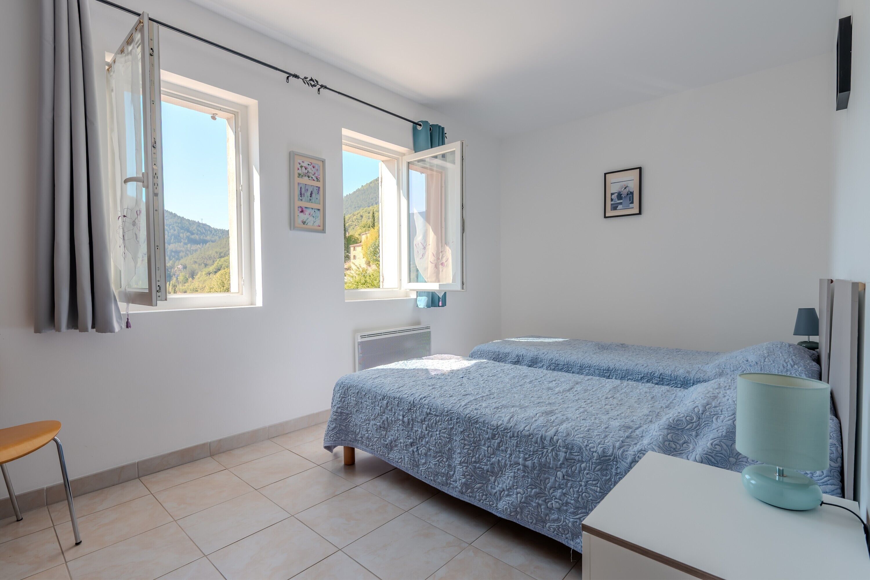 Une chambre avec deux lits, une chaise, un bureau et une fenêtre avec des rideaux.