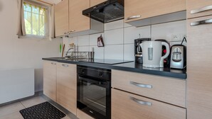 Une cuisine moderne avec des meubles en bois, un plan de travail noir, un four encastré et une bouilloire.
