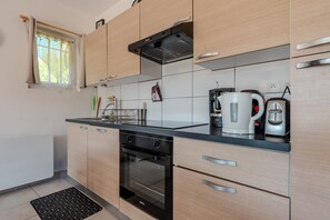 Una cocina moderna con armarios de madera, encimera negra, horno empotrado y hervidor.