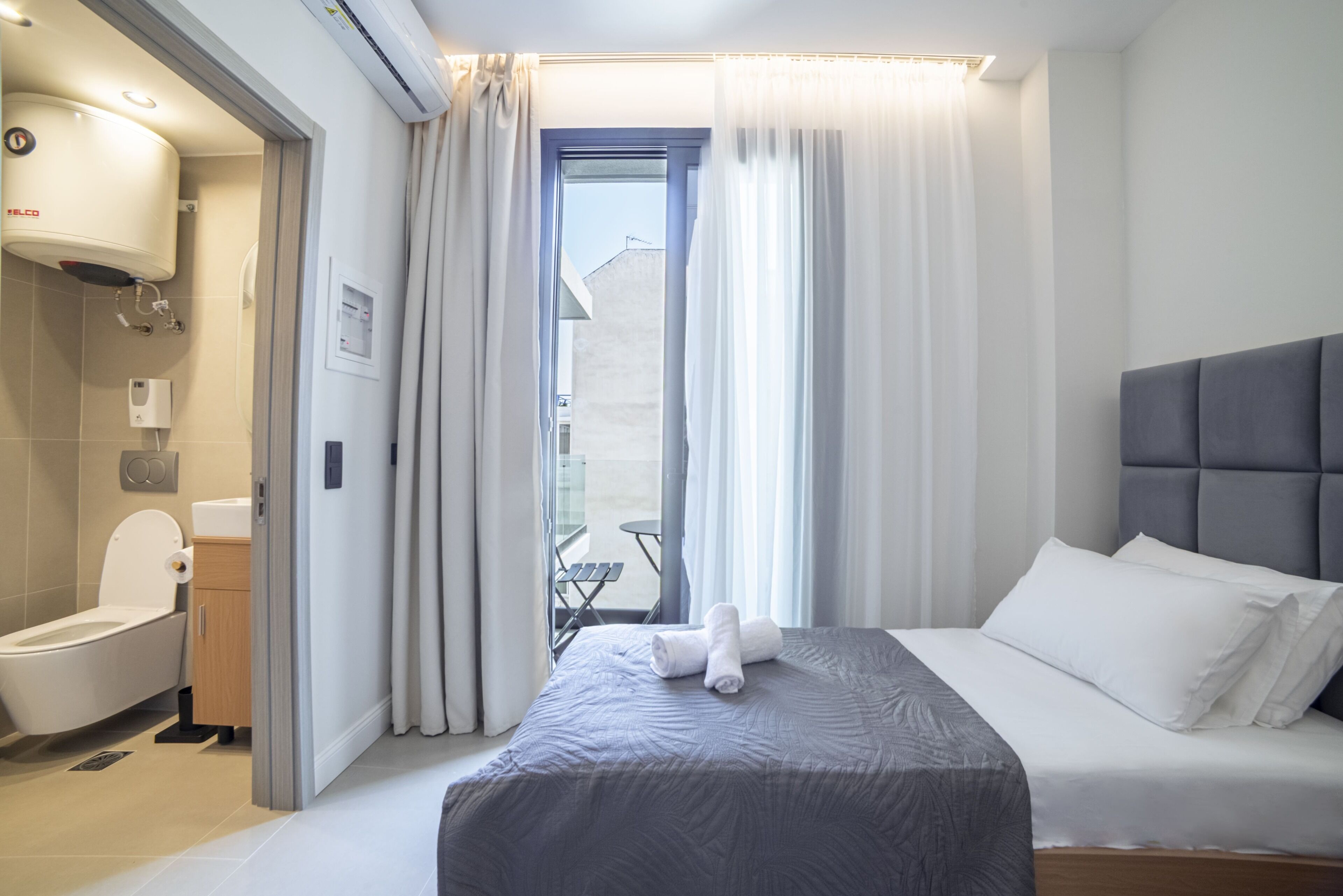 Hotellihuone, jossa on sänky, wc, suihku ja näkymä ulos.