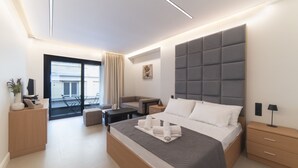 A modern hotel room with a large bed, a sofa, a desk, and a balcony with a view.