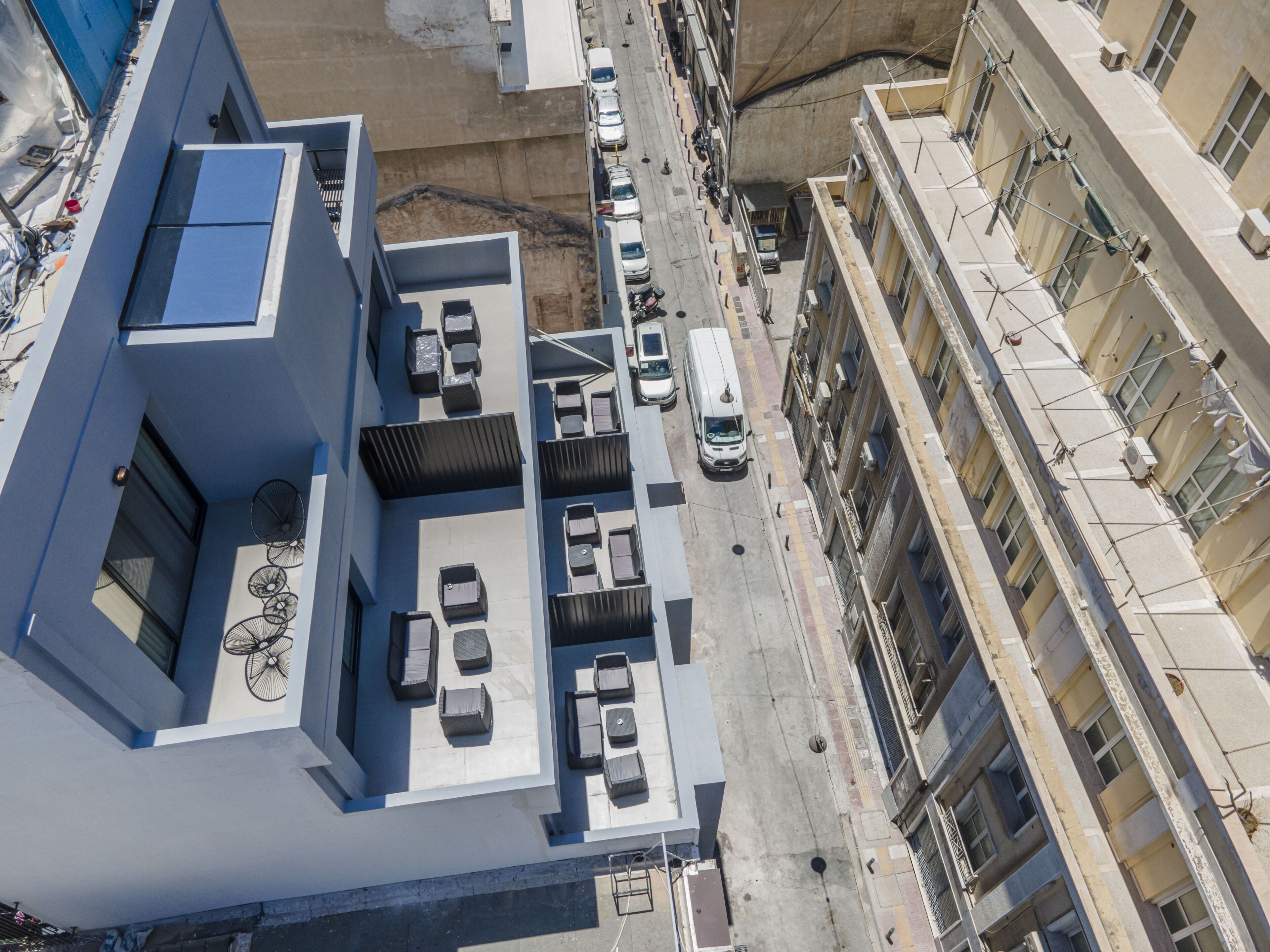 Un edificio alto con una terraza en la azotea, que cuenta con mesas al aire libre y un ventilador.