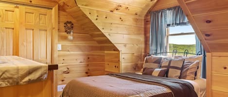 Un dormitorio de cabaña de madera con una cama litera, una ventana con cortinas y un adorno en la pared.