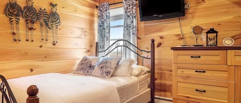 Una habitación con paneles de madera, una cama, un televisor, un aparador y decoración en la pared.
