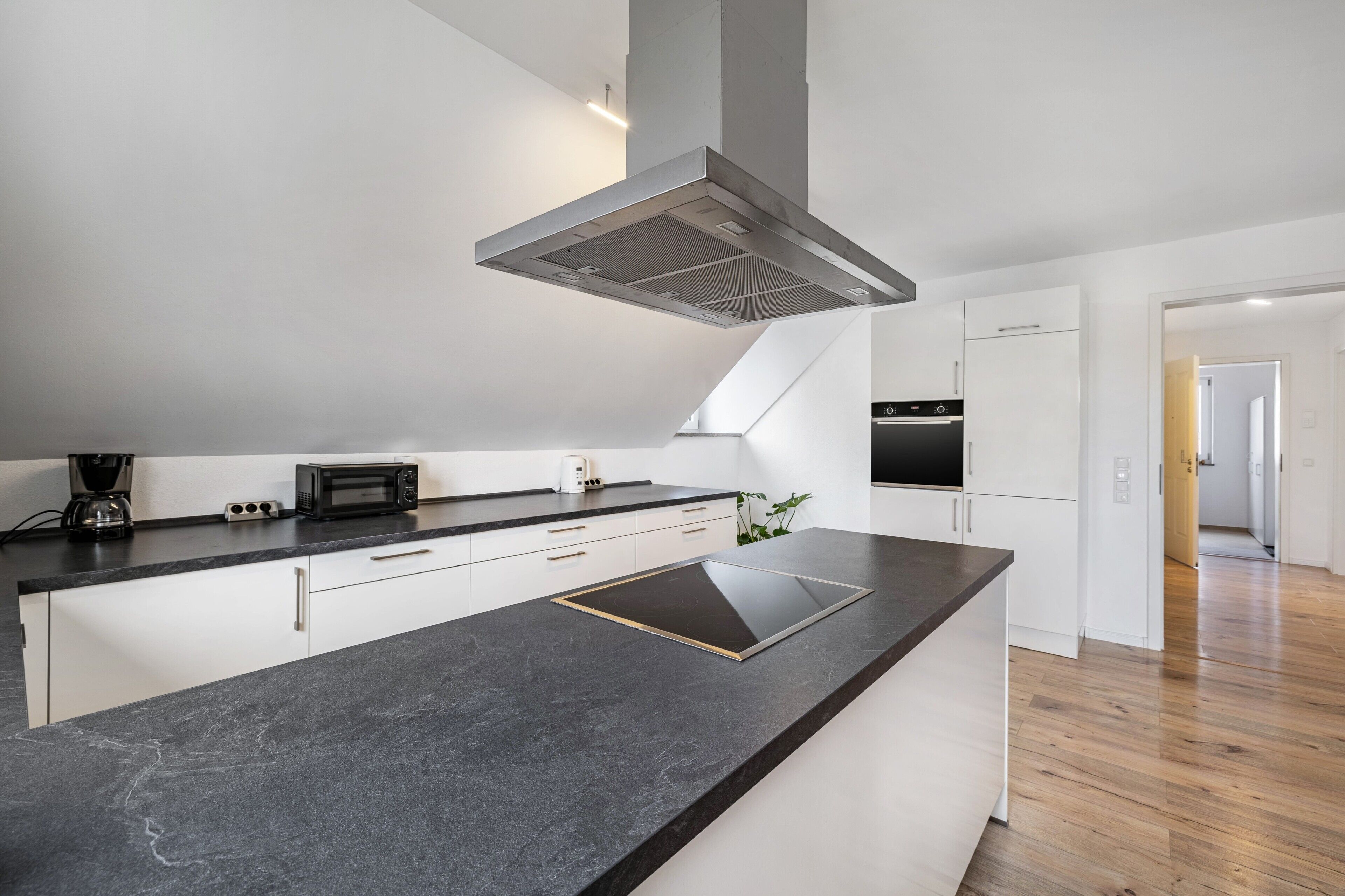 A modern kitchen with a black countertop, white cabinets, and a built-in oven.