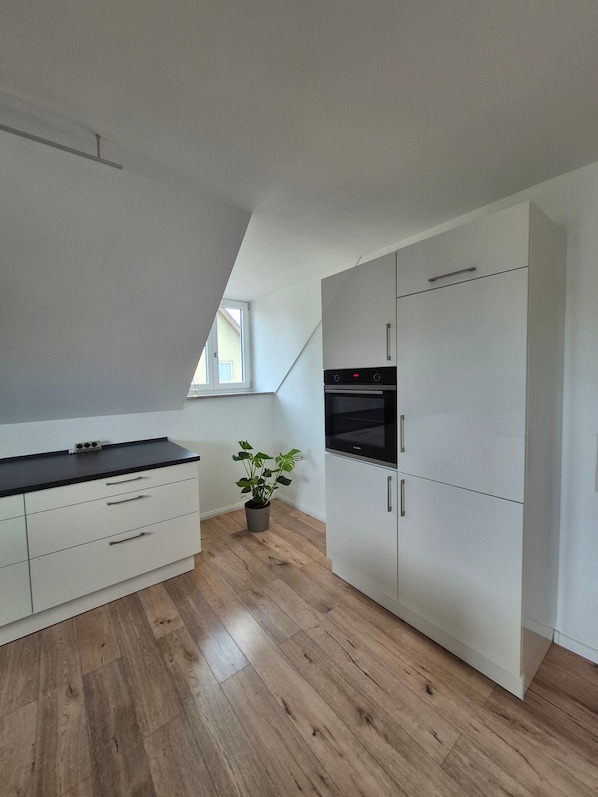 Eine moderne Küche mit weißen Schränken, einer schwarzen Arbeitsplatte und einem Blumentopf.