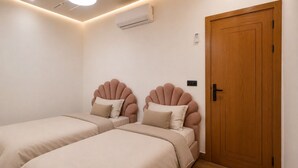 A bedroom with two beds, a wooden door, and an air conditioning unit.