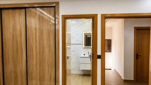 Ein Schlafzimmer mit einem Bett, einem Holzschrank und einem durch eine offene Tür einsehbaren Badezimmer.
