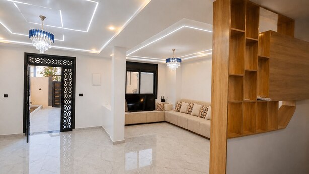A modern living room with a sectional sofa, a wooden built-in shelf, and a chandelier.