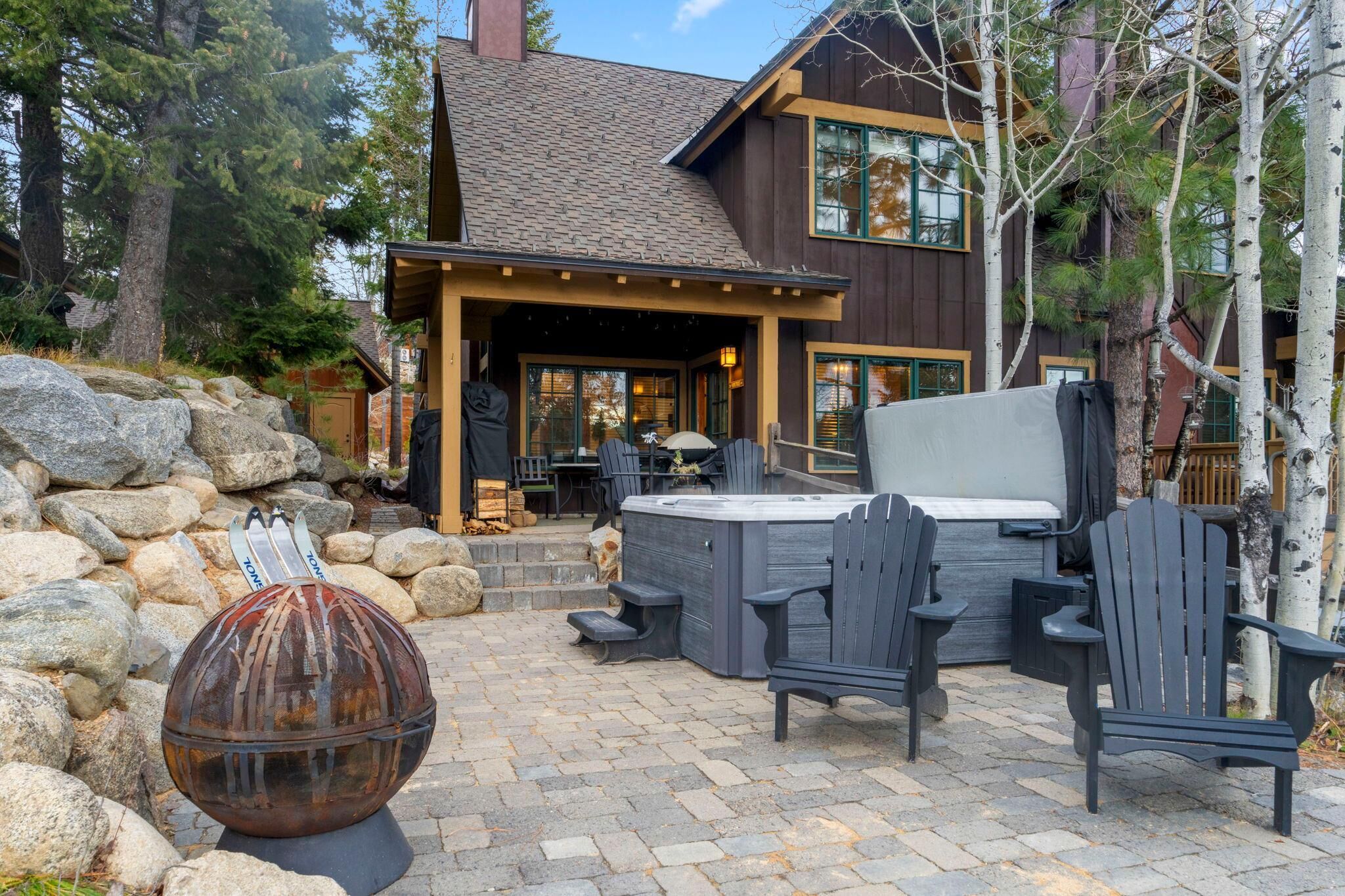 A wooden house with a patio area featuring outdoor furniture and a hot tub.