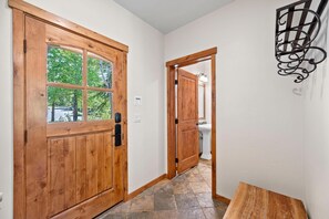 Eine Holztür mit Fenster, ein Korridor mit Fliesenboden und einer Wandleuchte.