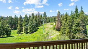 A view from a balcony overlooking a forested area with a ski lift. - Powderhound | Exclusive Tamarack Perks (Tamarack)