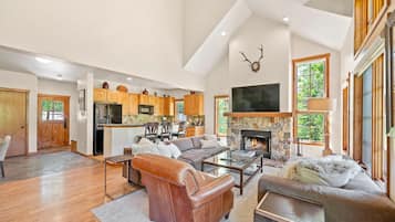 A spacious living area with a fireplace, a kitchen with wooden cabinets, and a large window.