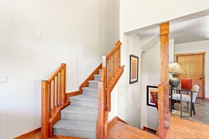 Eine Treppe mit Holzwangen und Teppichstufen führt zu einem Essbereich mit Tisch und Stühlen.
