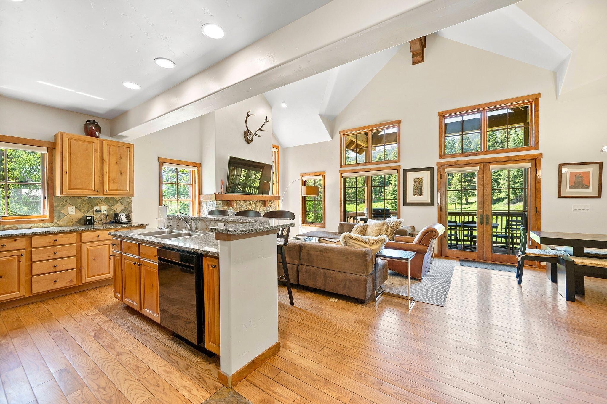 A spacious kitchen with wooden cabinets and a large island, a cozy living area with a fireplace, and large windows offering a view of the outdoors.