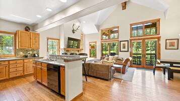 A spacious kitchen with wooden cabinets and a large island, a cozy living area with a fireplace, and large windows offering a view of the outdoors.