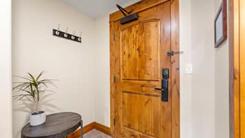 A wooden door with a handle and a keyhole, a small table with a potted plant, and a wall-mounted coat rack with hooks.
