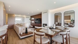 Una sala moderna con sofá, televisor, mesa de comedor, sillas y un espejo grande.
