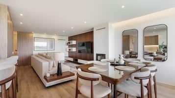 Uma sala de estar moderna com sofá, televisão, mesa de jantar, cadeiras e um espelho grande.
