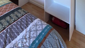 Une chambre avec une armoire, un lit avec une literie à motifs et des poutres en bois au plafond.