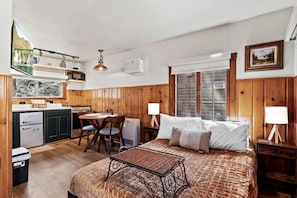 Ein Zimmer mit Bett, Esstisch, Küchenzeile und einem Fenster mit Blick.