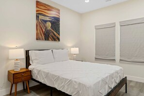 A bedroom with a bed, two bedside tables with lamps, a painting on the wall, and a window with blinds. - Peaceful Lake Retreat Near Lake Hartwell & Clemson, South Carolina (Westminster)