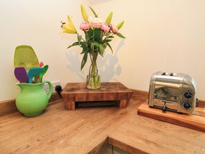 A kitchen counter with a green pitcher, a vase with flowers, a toaster, and a green colander. - The Farmhouse (Langport)