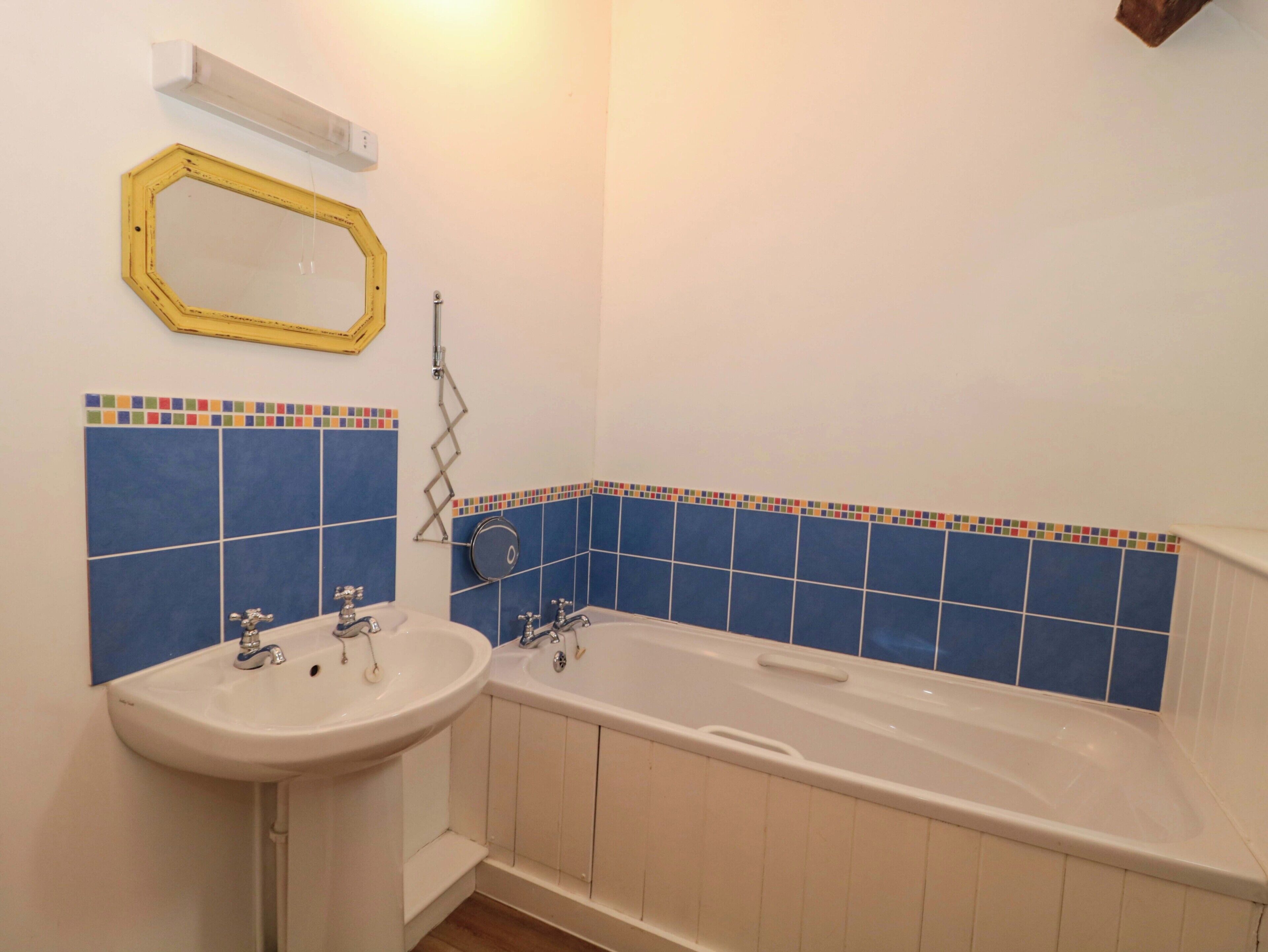Een badkamer met een badkuip, twee wastafels en een spiegel.