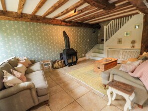 A cozy living room with a fireplace, a staircase, and a patterned wallpaper. - The Farmhouse (Langport)