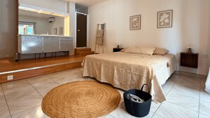 A bedroom with a bed, bedside tables, a mirror, and a bathroom with a sink and vanity. - Group house in Provence with a pool, ping-pong, pétanque, and billiards (Orange)