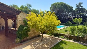 A stone building with a pergola, a tree, and a swimming pool in a landscaped yard. - Group house in Provence with a pool, ping-pong, pétanque, and billiards (Orange)