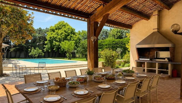 An outdoor dining area with a pool view, a grill, and a pergola. - Group house in Provence with a pool, ping-pong, pétanque, and billiards (Orange)
