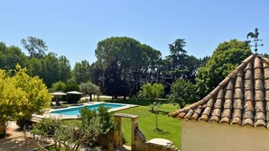 A swimming pool surrounded by a well-maintained lawn, stone structures, and trees. - Group house in Provence with a pool, ping-pong, pétanque, and billiards (Orange)
