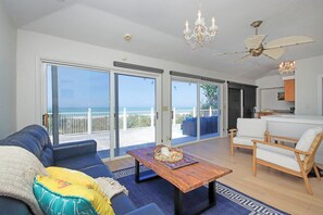 A spacious living area with a sofa, coffee table, and chairs, a balcony with a view of the sea, and a ceiling fan. - Beachfront Private Pool Home - Sanibel Shuffle Beach House (Sanibel Island)