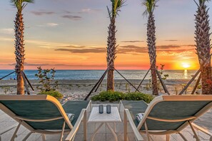 A sunset view from a lounge area with two chairs and a table, overlooking the beach and ocean. - NEW! Ibis Cottage | Direct Beachfront Retreat on Manasota Key (Englewood)