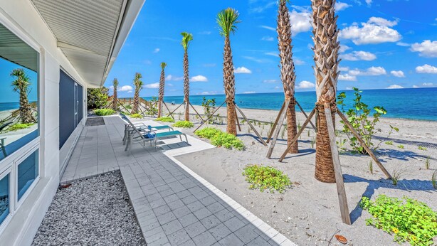 Ein Hotel am Strand mit einer Terrassenanlage, Palmen und Meerblick.