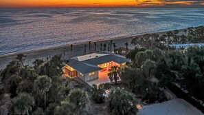 A beachfront property with a house, palm trees, and ocean views. - NEW! Ibis Cottage | Direct Beachfront Retreat on Manasota Key (Englewood)