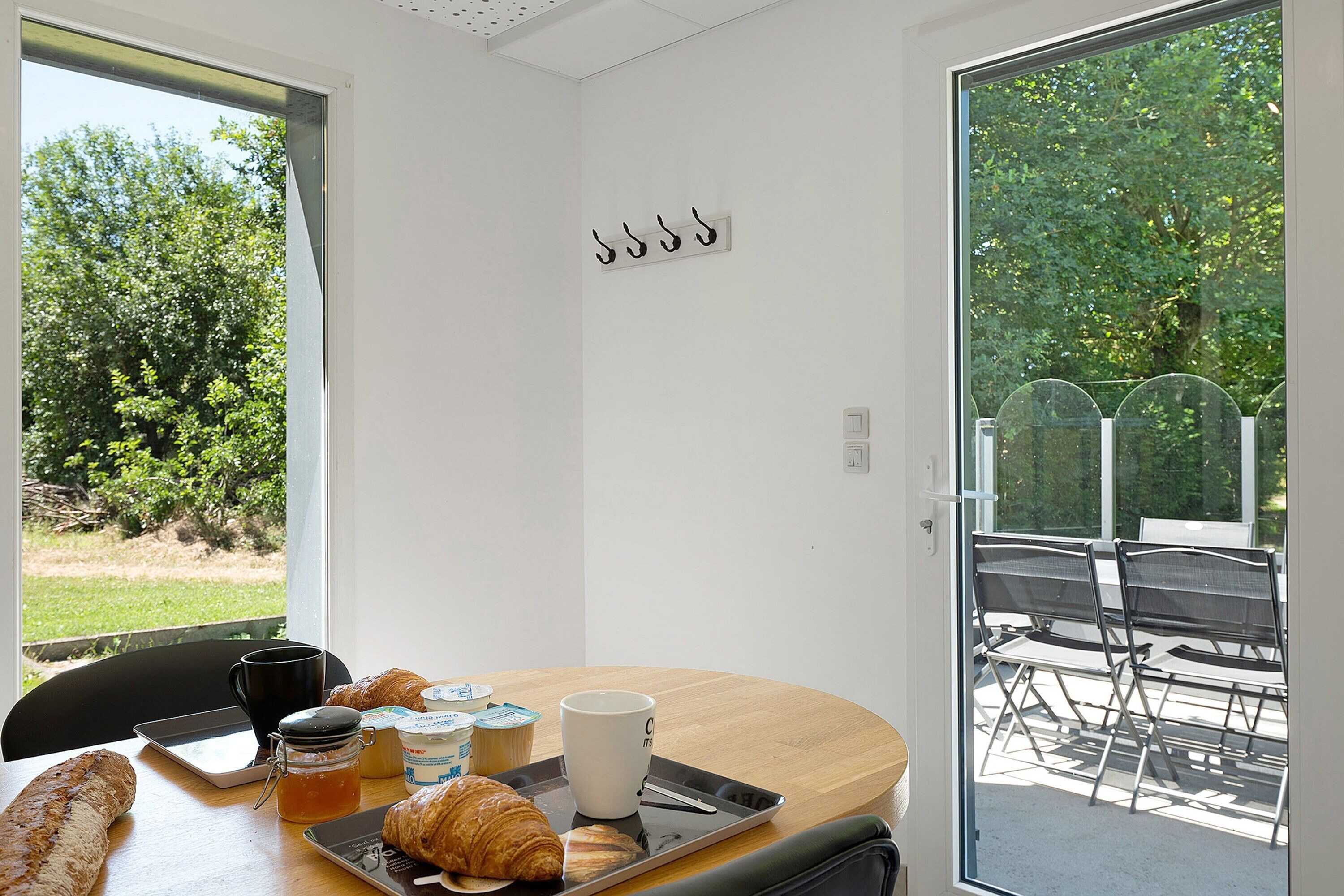 A breakfast table with croissants, a coffee cup, and a tablet.